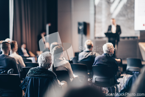 Image of Speaker giving a talk in conference hall at business event. Rear view of unrecognizable people in audience at the conference hall. Business and entrepreneurship concept.