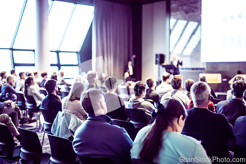 Image of Speaker giving a talk in conference hall at business event. Rear view of unrecognizable people in audience at the conference hall. Business and entrepreneurship concept.