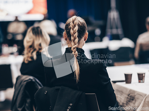 Image of Rear view of a unrecognizable business woman wearing beautiful hair bun attending conference business meeting.