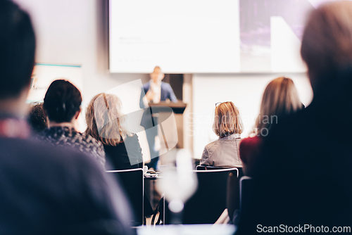 Image of Speaker giving a talk in conference hall at business event. Rear view of unrecognizable people in audience at the conference hall. Business and entrepreneurship concept.