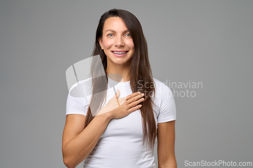Image of Woman smiling with one hand on chest expressing sincerity and positive emotion