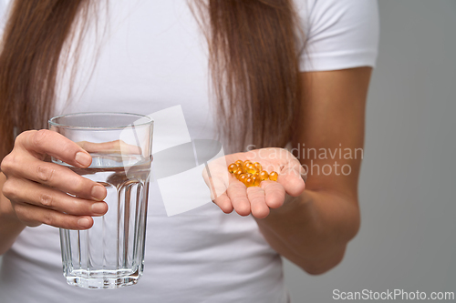 Image of Close-up of woman holding glass of water and vitamins in hand