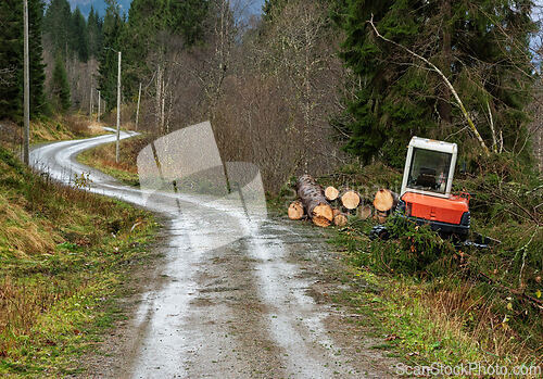 Image of Heavy machinery and cut timber along a winding forest road in au