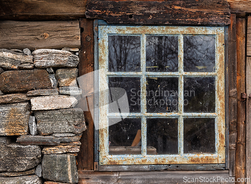 Image of Rustic wooden cabin window framed by stone with a weathered appe