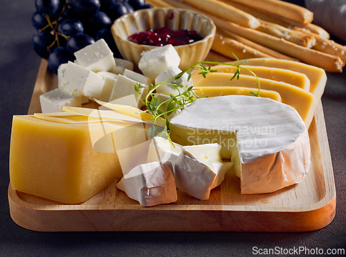 Image of cheese plate and bread sticks on dark grey table