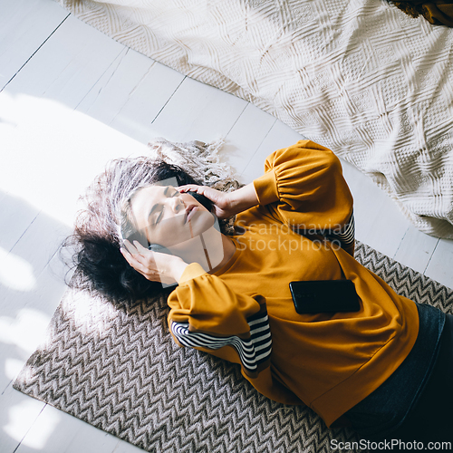 Image of Single woman in her 40s relaxing in her cozy home interior and h