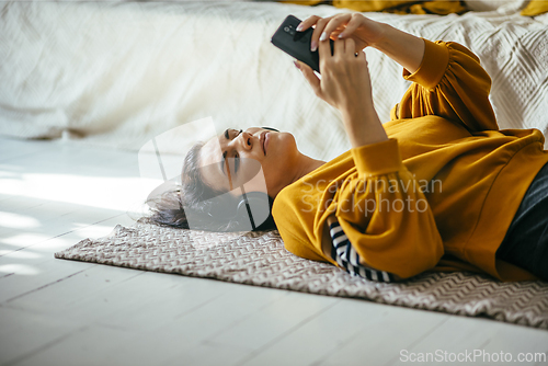 Image of Single woman in her 40s relaxing in her cozy home interior and h