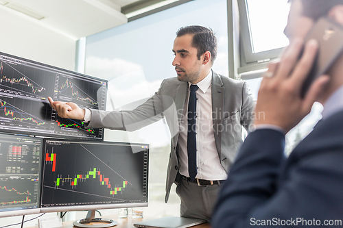 Image of Stock brokers looking at computer screens, trading online.
