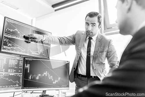Image of Stock brokers looking at computer screens, trading online.