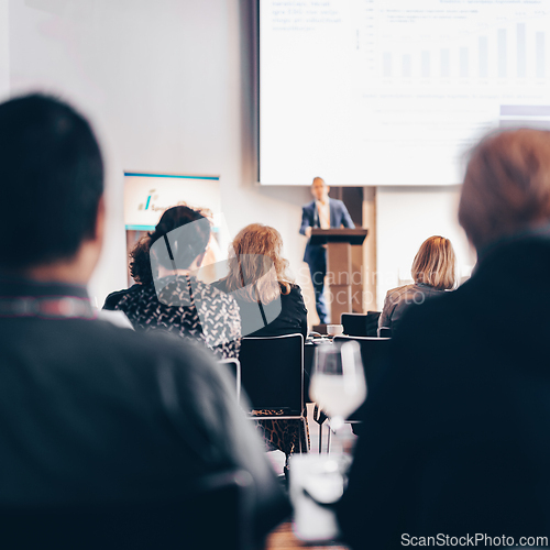 Image of Speaker giving a talk in conference hall at business event. Rear view of unrecognizable people in audience at the conference hall. Business and entrepreneurship concept.