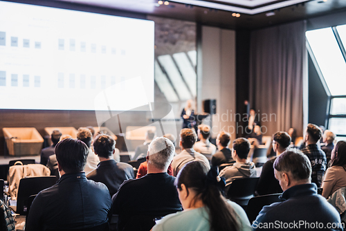 Image of Female speaker giving a talk on corporate business conference. Unrecognizable people in audience at conference hall. Business and Entrepreneurship event.