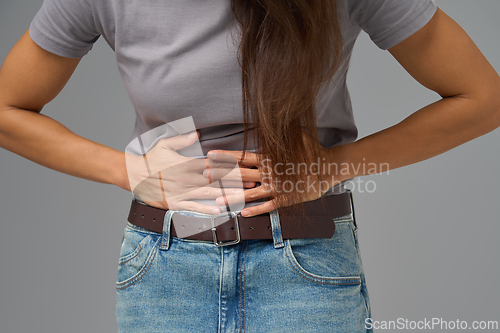 Image of Midsection view of woman pressing lower abdomen with both hands, studio shot