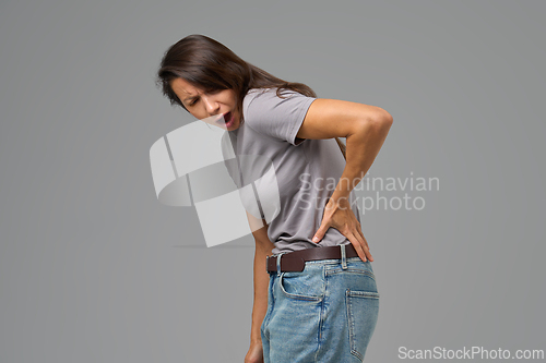 Image of Woman with hand on lower back grimacing in pain, image with neutral background