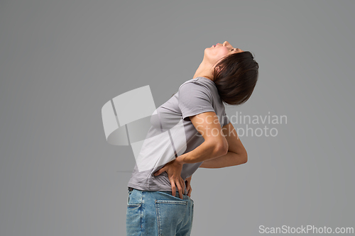 Image of Woman bending backward with hands on lower back, grimacing in discomfort