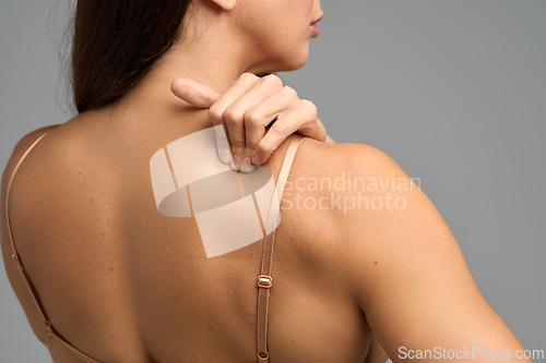Image of Woman touching neck and shoulder showing muscle strain and upper back pain