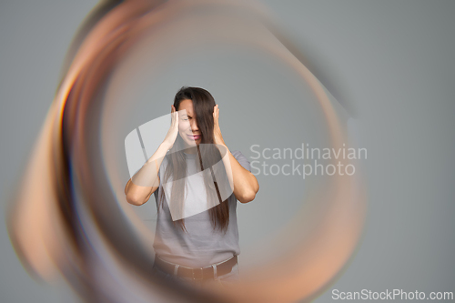 Image of Woman holding head in pain surrounded by circular distortion symbolizing migraine or tinnitus