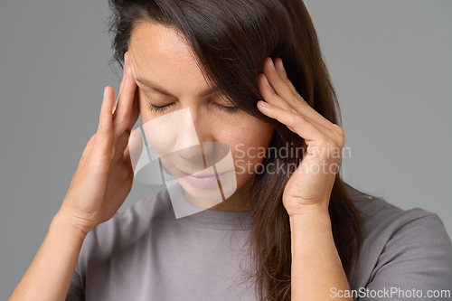 Image of Close-up portrait of woman pressing temples with eyes closed, concept of stress