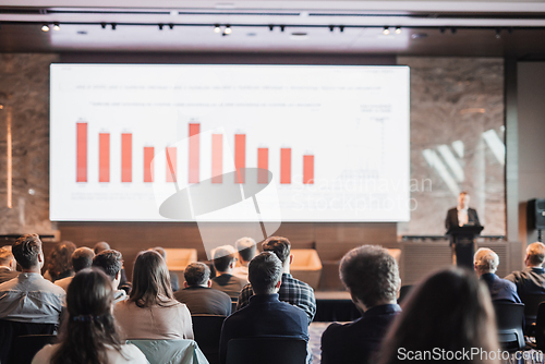 Image of Speaker giving a talk in conference hall at business event. Rear view of unrecognizable people in audience at the conference hall. Business and entrepreneurship concept.