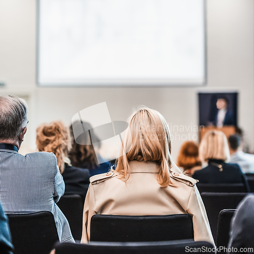 Image of Speaker giving a talk in conference hall at business event. Rear view of unrecognizable people in audience at the conference hall. Business and entrepreneurship concept.