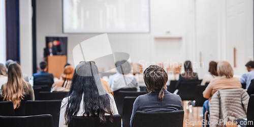 Image of Speaker giving a talk in conference hall at business event. Rear view of unrecognizable people in audience at the conference hall. Business and entrepreneurship concept.