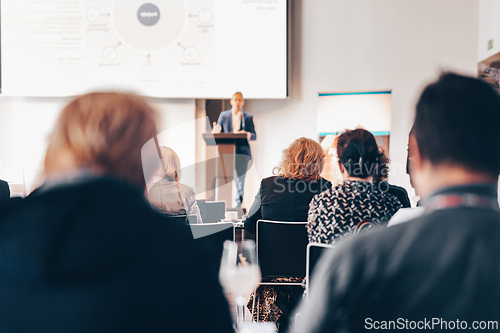 Image of Speaker giving a talk in conference hall at business event. Rear view of unrecognizable people in audience at the conference hall. Business and entrepreneurship concept.