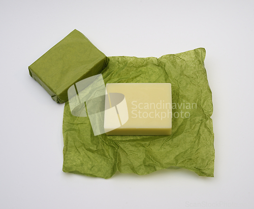 Image of bar of soap on green paper wrapper on white