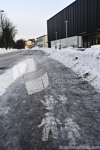 Image of  Ice covered sidewalk with a pedestrian path sign 