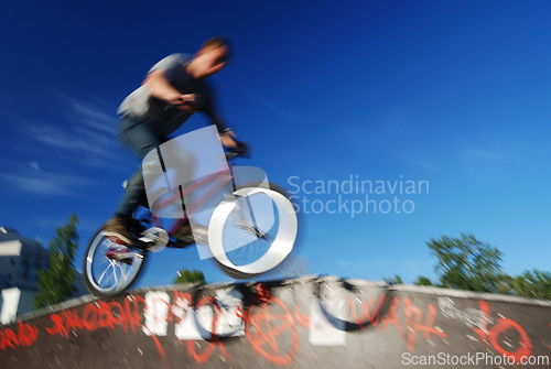 Image of cyclist jumping against the blue sky, blurry photo 
