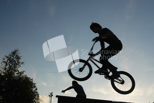 Image of cyclist jumping against the blue sky, blurry photo 
