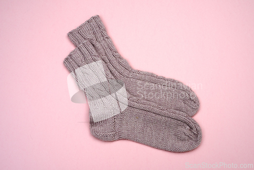 Image of knitted wool socks on a pink background 