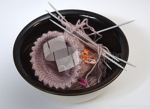 Image of knitting from wool and knitting needles in a ceramic bowl 
