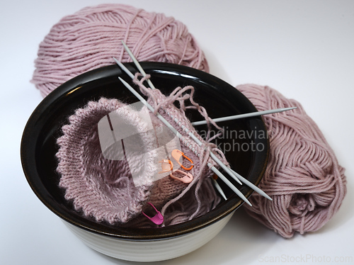 Image of knitting from wool and knitting needles in a ceramic bowl 