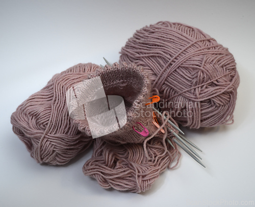Image of knitting from pink wool and knitting needles 