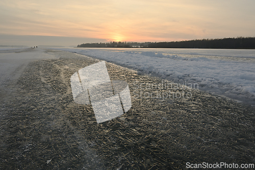 Image of sunset over a winter lake and an icy road for skating  