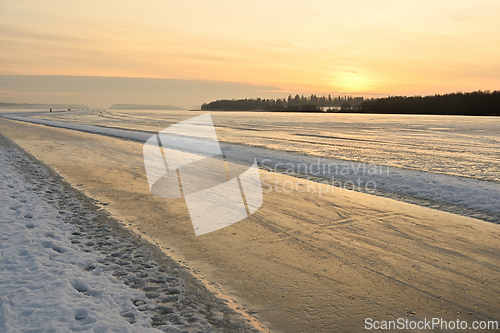 Image of sunset over a winter lake and an icy road for skating  