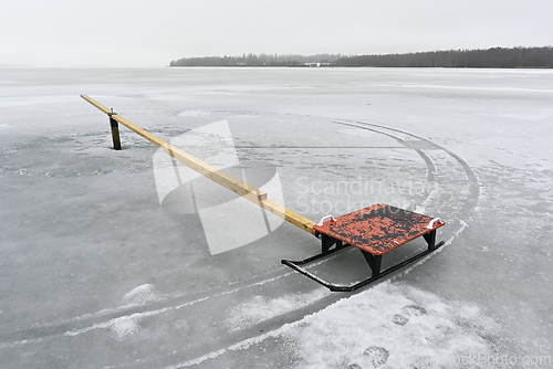 Image of Frozen lake wih red sleigh and wtooden plank