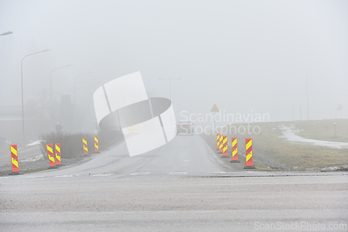 Image of foggy road with roadwork signs and car 