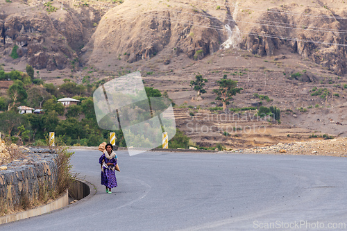 Image of Local woman in traditional clothing walks along the highway in the mountainous Amhara Region. Ethiopia