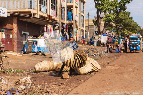 Image of Ethiopian man offers hand-woven traditional items to pedestrians on the street. Demebecha, Ethiopia