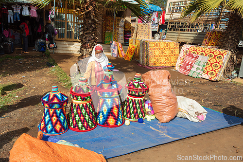 Image of Ethiopian woman selling culturally significant mesob baskets on a dusty lot in Demebecha. Ethiopia