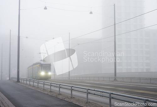 Image of a city tram travels through the city in heavy fog 