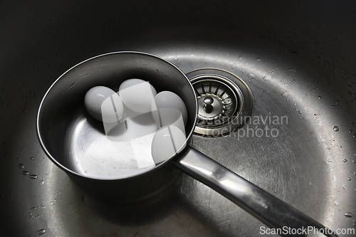 Image of boiled chicken eggs in a metal pot in the sink 