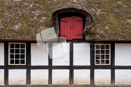 Image of Red door on thatched roof house with white walls and dark wooden