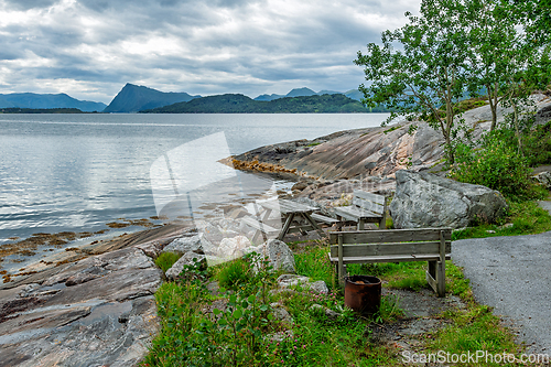 Image of Scenic coastal view with benches and rocks near water on a cloud