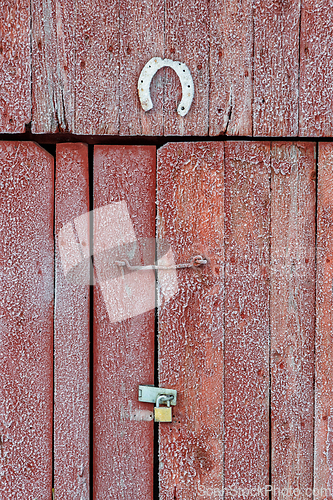 Image of Rustic wooden barn door adorned with a horseshoe and secured wit