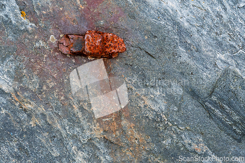 Image of Rustic textures of rock with vivid red minerals glimmering under