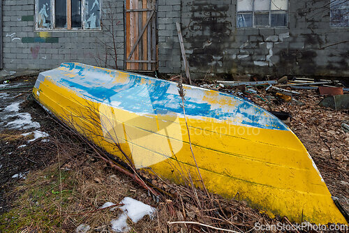 Image of Abandoned boat resting in the overgrown yard of an old building,