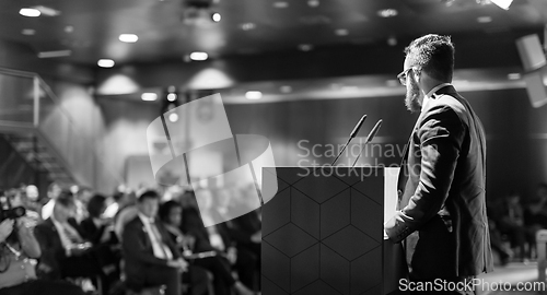 Image of Public speaker giving talk at business event.