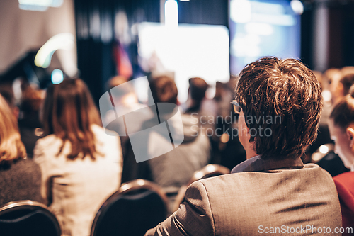 Image of Speaker giving a talk in conference hall at business event. Rear view of unrecognizable people in audience at the conference hall. Business and entrepreneurship concept.