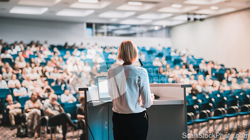 Image of Female speaker giving a talk on corporate business conference. Unrecognizable people in audience at conference hall. Business and Entrepreneurship event.